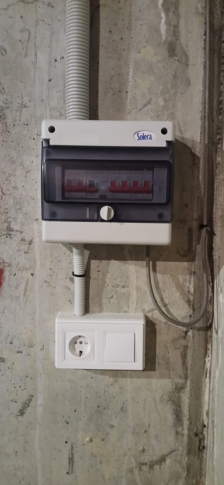 Cuadro estanco con protecciones y toma de corriente instalado en la pared de un garaje